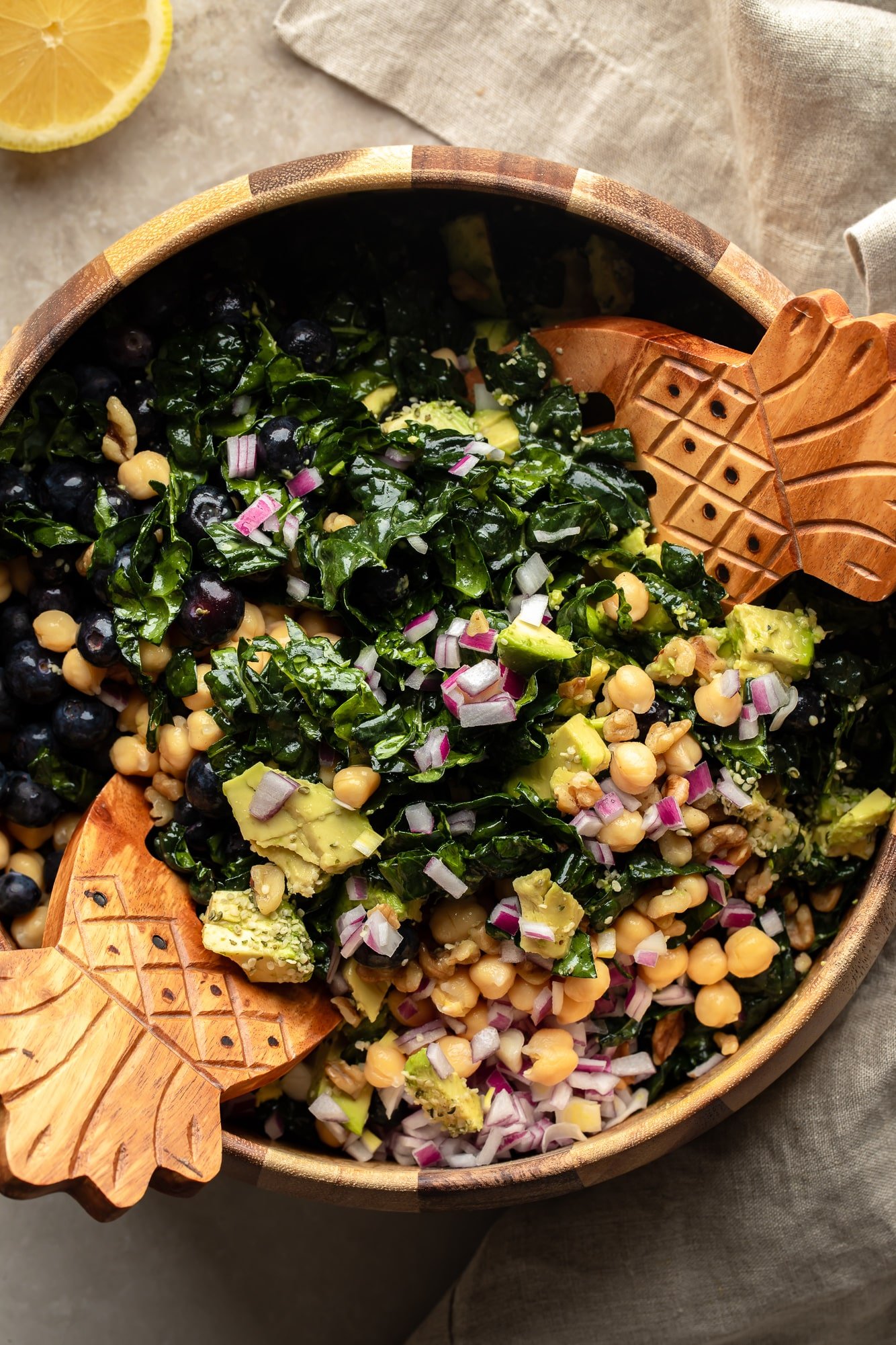 Usando 2 pinças para jogar uma salada de couve juntos em uma tigela grande.