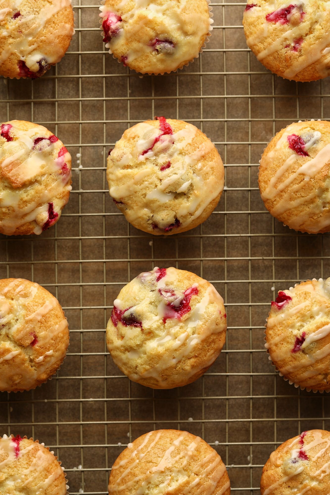 Os muffins laranja de cranberry envidraçados em uma gradinha.