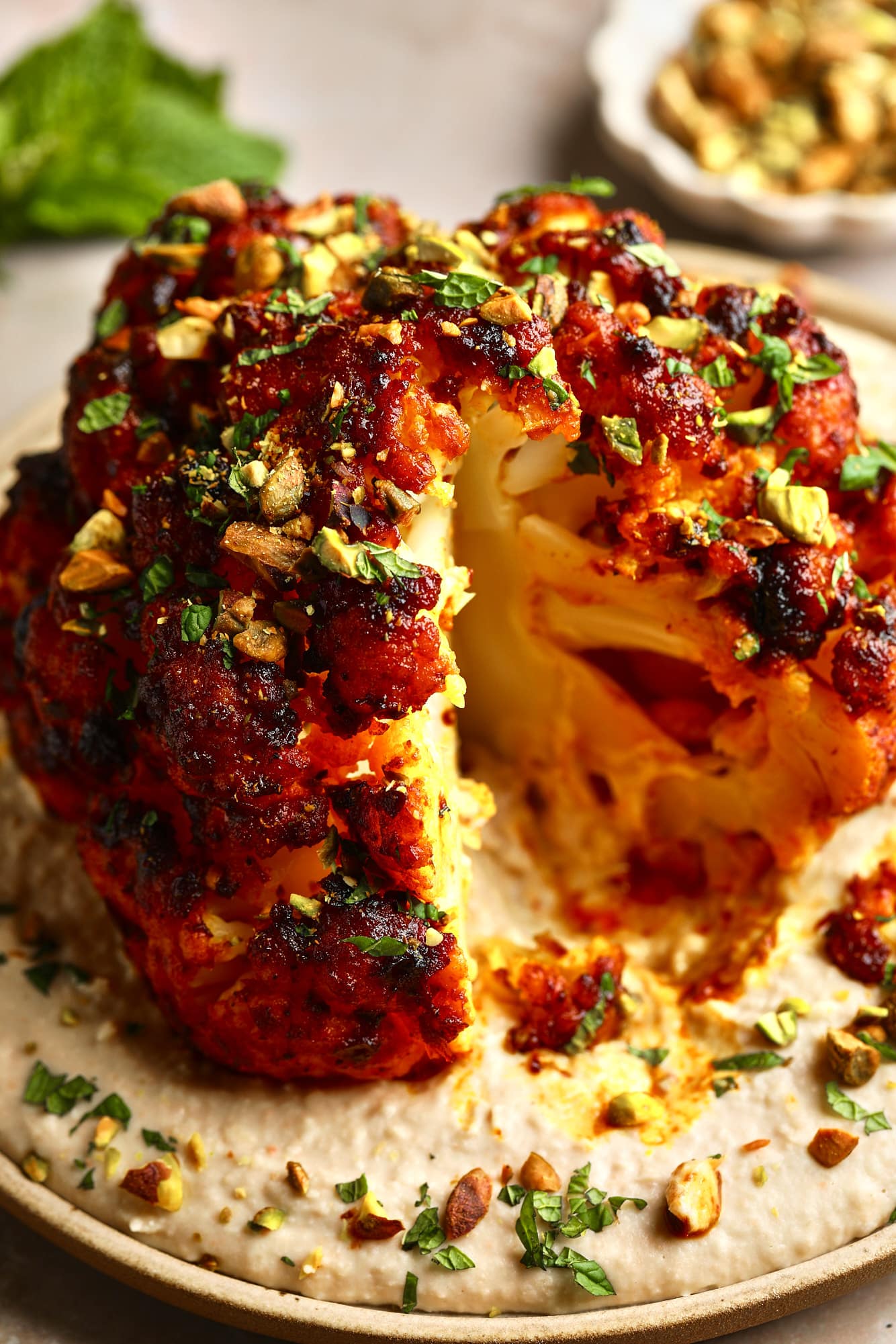 Feche em uma cabeça de couve-flor assada em fatias de Harissa em um feijão branco espalhado em um prato.